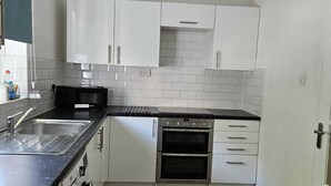 A modern kitchen with white cabinets, a black countertop, and a built-in oven.