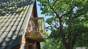 A wooden balcony with a metal roof, surrounded by trees. - Lodge 68 - Fern Gully (Newton Abbot)