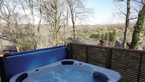 A hot tub on a deck with a view of a residential area. - Acorn Lodge (Newton Abbot)