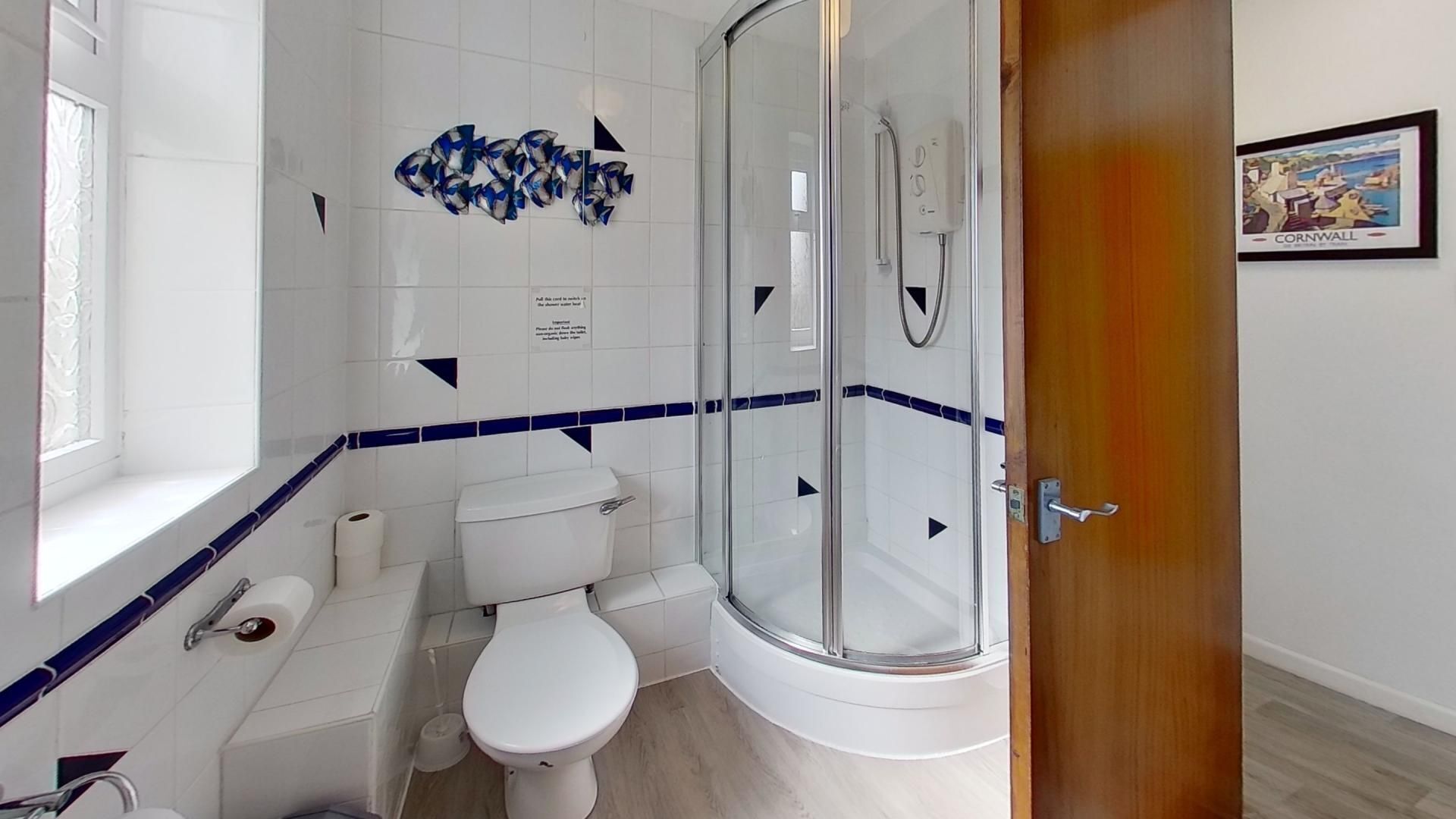 A bathroom with a toilet, a glass shower enclosure, and a window.