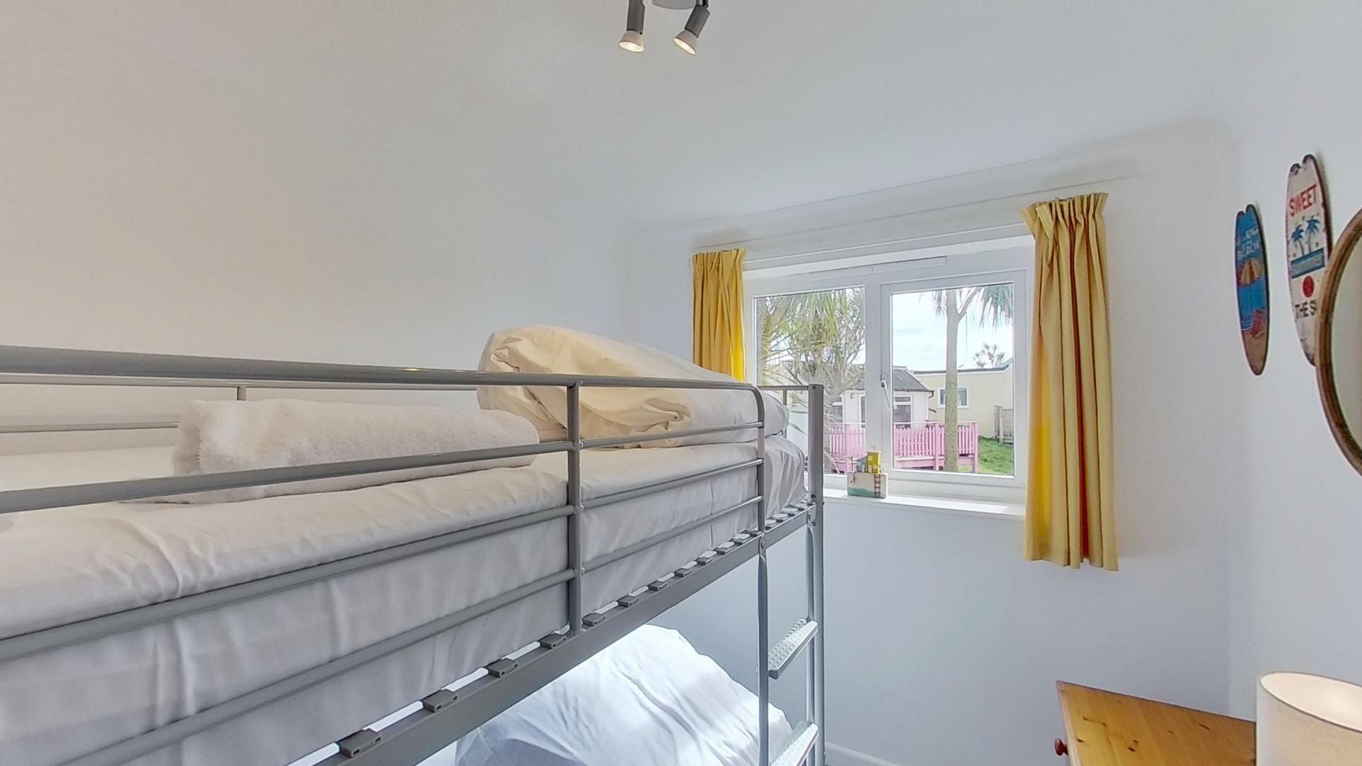 A bunk bed room with a window, curtains, and a wall with a poster.