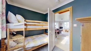 Een kamer met stapelbedden, een bureau, een stoel en een televisie.