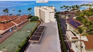 A hotel with a basketball court, solar panels, and a view of the ocean. - Kona Alii 206 (Kailua-Kona)
