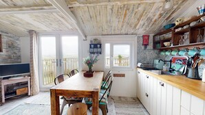 A cozy kitchen with wooden cabinets, a dining table, and a TV on a stand. - E41 Silver Mist, Riviere Towans (Hayle)