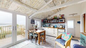 A cozy kitchen with a view, featuring a wooden table, chairs, and a dining area. - E41 Silver Mist, Riviere Towans (Hayle)