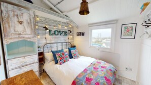 A bedroom with a bed, a dresser, a window, and a wall with 'LOVE' spelled out in lights. - E41 Silver Mist, Riviere Towans (Hayle)