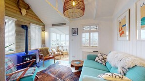 A cozy living room with a fireplace, comfortable seating, and artwork on the walls. - F12 West View, Riviere Towans (Hayle)