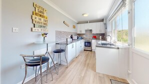 A modern kitchen with white cabinets, a built-in oven, and a window.