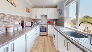 A modern kitchen with white cabinets, a stainless steel oven, a microwave, and a sink.