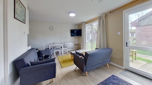 A modern living room with two grey sofas, a small white table, and a TV mounted on the wall. - 59 Trevithick Court, Tolroy Manor (Hayle)