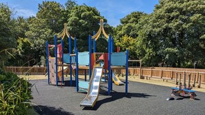 A playground with a slide, climbing structures, and swings. - 58 Trevithick Court, Tolroy Manor (Hayle)