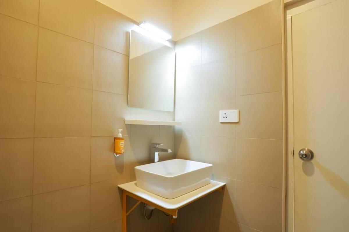 A bathroom with a white sink, a mirror, and a soap dispenser.