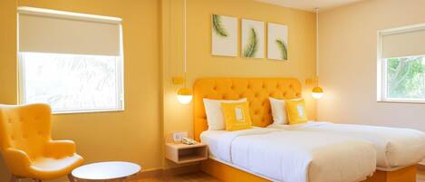 A hotel room with a large bed, a chair, a small table, and artwork on the wall.