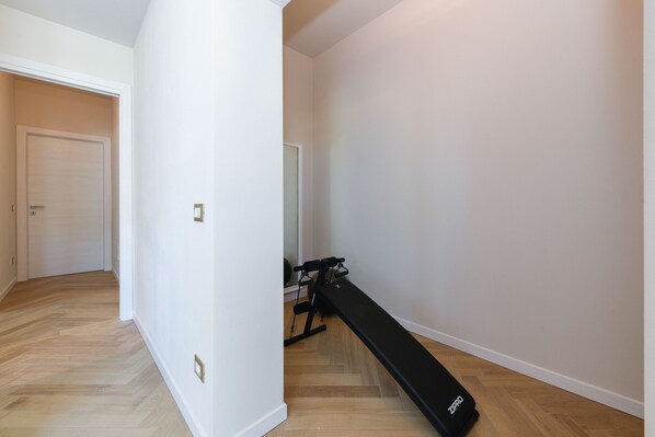 A room with a wooden floor, a black exercise bench, and a door. - Gardaliva 6 by the lake in Manerba del Garda (Manerba del Garda)