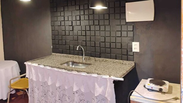 Een kleine keuken met een granieten aanrecht, een spoelbak en een wit decoratief tafelkleed.
