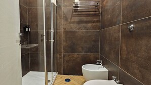 Un baño moderno con cabina de ducha de vidrio, lavamanos y tocador.