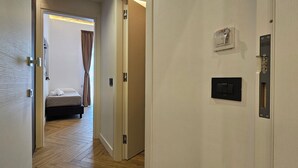 Una habitación de hotel con una cama, una puerta con cerradura y un panel de control montado en la pared.