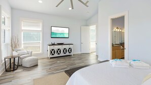 A bedroom with a large bed, a television, a dresser, and a bathroom mirror.