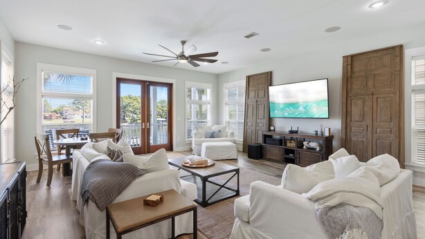 A spacious living room with a ceiling fan, a flat-screen TV, and a dining area with a table and chairs.