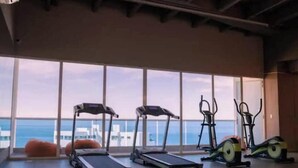A gym with treadmills, an elliptical, and a stationary bike, large windows with a view of the sea. - Reserva del Mar: Condominium with Ocean View (Santa Marta, Gaira)