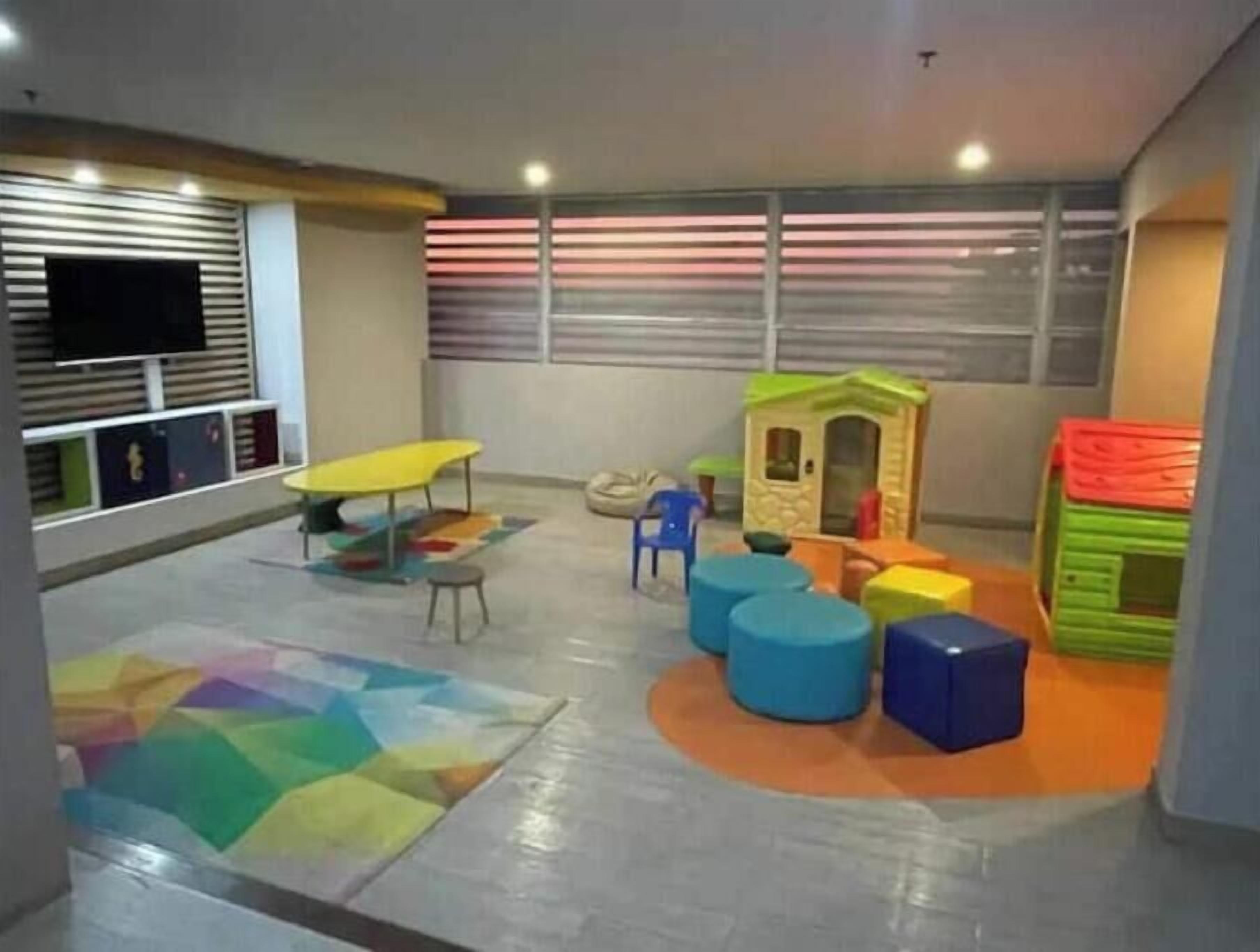 A children's play area with a playhouse, colorful stools, and a table.
