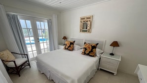 A bedroom with a large bed, two nightstands, a chair, and a window with curtains.