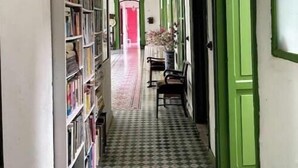 A narrow hallway with a checkered floor, green doors, and a bookshelf on one side. - Private room for 2 l Palermo, Antioquia (Támesis)