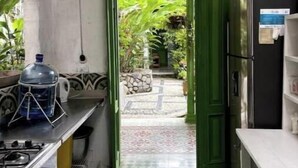 Eine Küche mit einer grünen Tür, die auf eine Terrasse führt, einem Wasserspender und einem Kühlschrank.