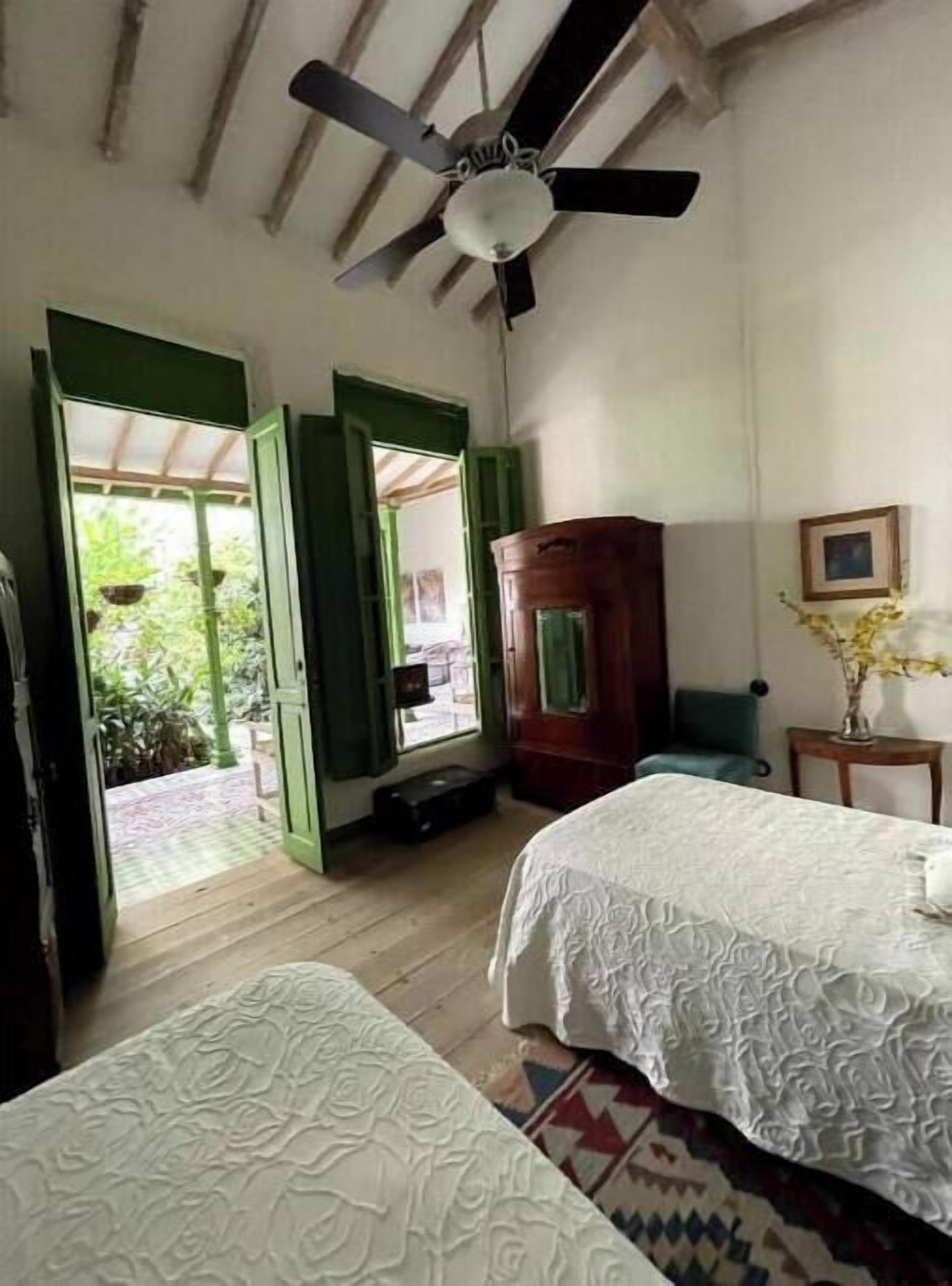 A bedroom with two beds, a ceiling fan, a wardrobe, and a view of the outdoors.