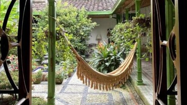 An entrance with a hammock, a tiled pathway, and a green fence. - Room for couples in Palermo - Antioquia (Támesis)
