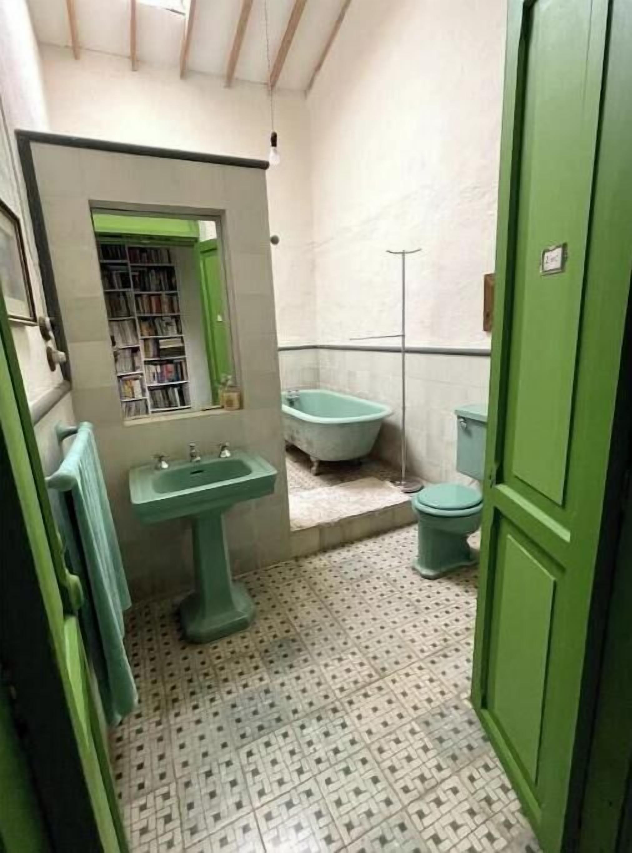 Une petite salle de bain avec un lavabo vert, une baignoire et des toilettes.