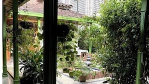 A covered outdoor area with a tiled floor, green pillars, and potted plants.