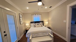 A bedroom with a bed, bedside tables, a ceiling fan, and a window with blinds. - Easy Living In Delightful Duplex (Lubbock)