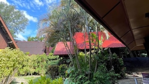 A covered outdoor area with a red-roofed structure, surrounded by lush greenery and a clear blue sky. - The Reef Bluestar Perhentian (Pulau Perhentian Besar)