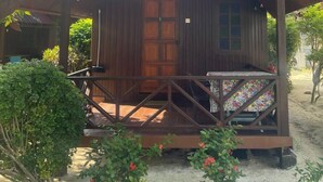 A wooden cabin with a porch, surrounded by greenery and palm trees. - The Reef Bluestar Perhentian (Pulau Perhentian Besar)