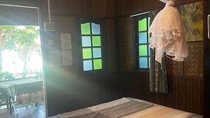 A room with a bed, a ceiling fan, a mosquito net, and a window with a view of greenery. - The Reef Bluestar Perhentian (Pulau Perhentian Besar)