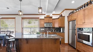 A modern kitchen with wooden cabinets, stainless steel appliances, and a central island with a sink.