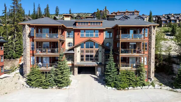 A multi-story lodge with a stone facade, large windows, and balconies.