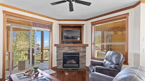 A living room with a fireplace, leather sofa, and a television mounted above it.