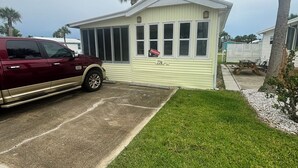 Ein Bungalow mit kleinem Vorgarten, geparktem Fahrzeug und Picknicktisch.