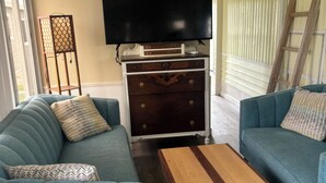 Ein Wohnzimmer mit Sofa, Couchtisch, Fernseher und einem dekorativen Schrank.