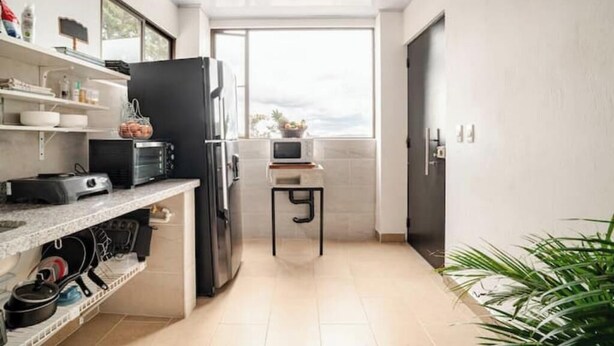 A compact kitchen with a refrigerator, microwave, and a small table with a plant. - Comfortable and spacious apartment in Usaquén Bogotá (Bogotá, D.C.)