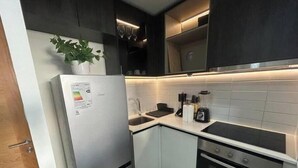 A modern kitchen with a refrigerator, sink, stove, and cabinets.