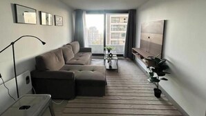 A modern living room with a sectional sofa, a coffee table, and a TV on a wooden floor.