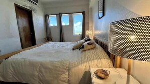 Ein Hotelzimmer mit einem großen Bett, einer Nachttischlampe und einem Fenster mit Vorhängen.