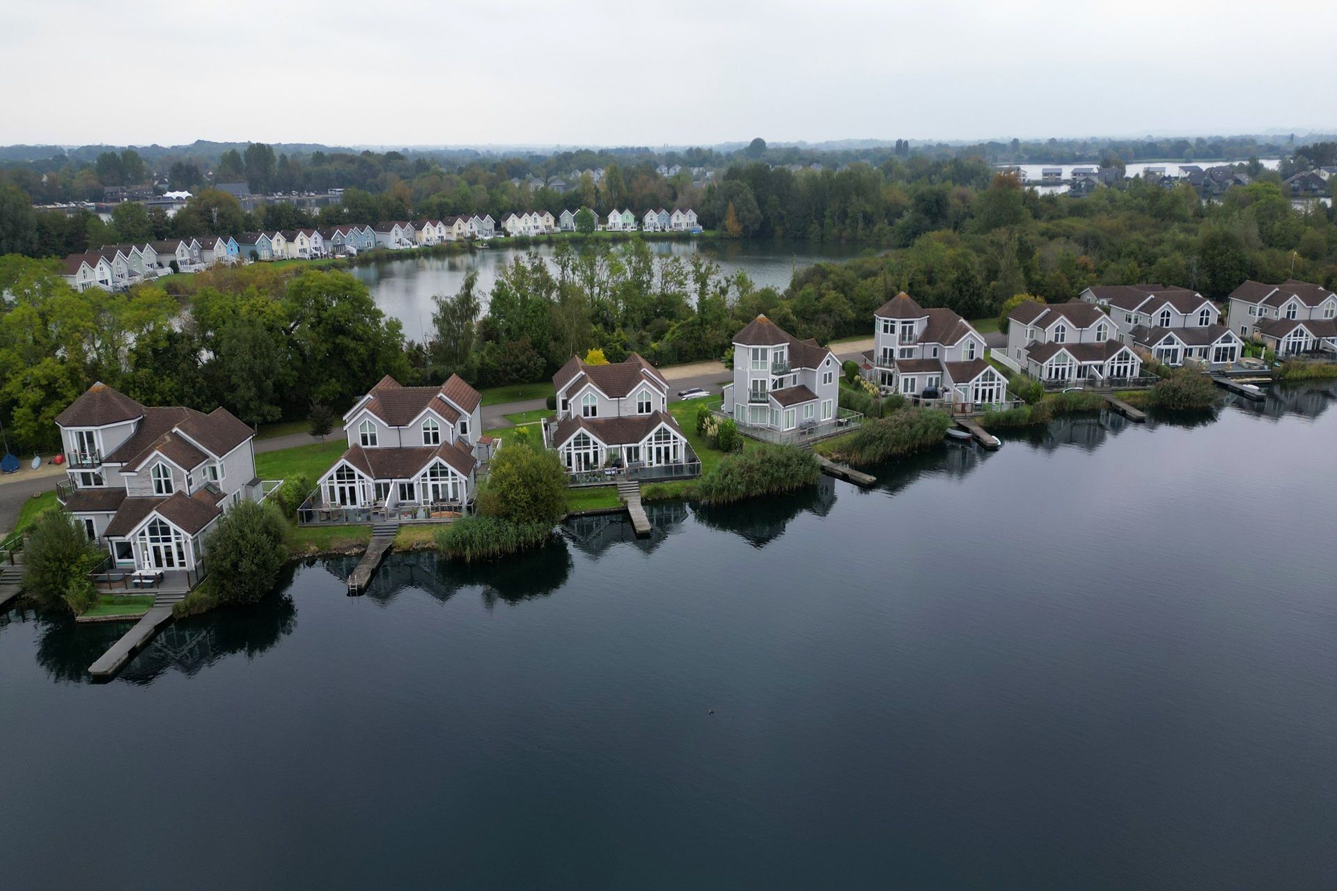 A row of white houses with brown roofs, connected by a narrow waterway.