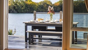 An outdoor dining area with a table set for four, overlooking a body of water and surrounded by trees. - The Landings 18, Waters Reach (P) - Lakeside Luxury, Hot Tub, Tennis, Sleeps 10 (South Cerney)
