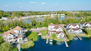 Een woonwijk met huizen aan een meer, inclusief een steiger en een rij huizen op de achtergrond.