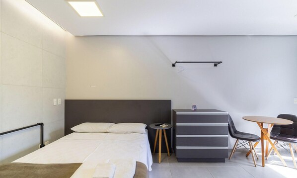 Habitación de hotel moderna con cama, escritorio, dos sillas y una mesita.
