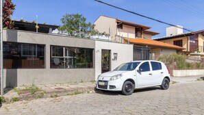 Ein weißes Auto parkt vor einem Gebäude mit einem großen Fenster und einer Tür, die mit der Nummer 175 gekennzeichnet ist.